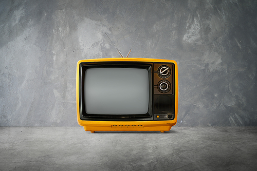 Yellow Orange color old vintage retro Television on cement table with  background .