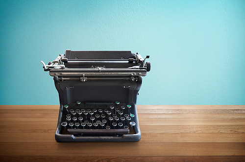 Old vintage retro black Typewriter on wood table with mint blue background