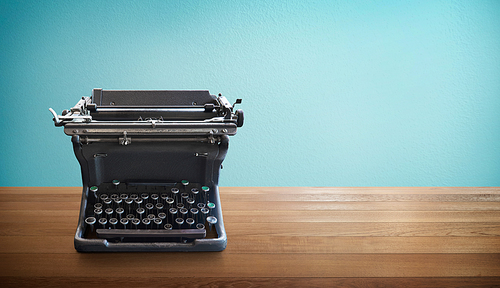 Old vintage retro black Typewriter on wood table with mint blue background