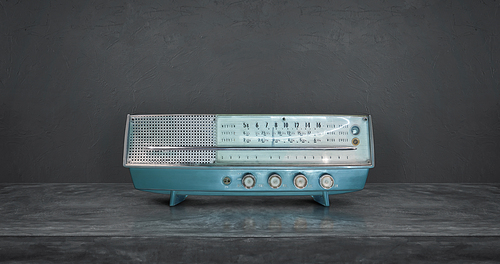 Old antique AM FM stereo radio isolated on cement wall and floor background .