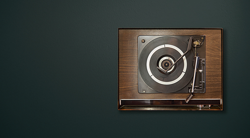 Old vintage retro wooden vinyl record player on green background , oldy music entertainment , top view .