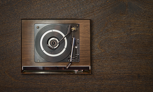 Old vintage retro wooden vinyl record player on wooden background , oldy music entertainment , top view .