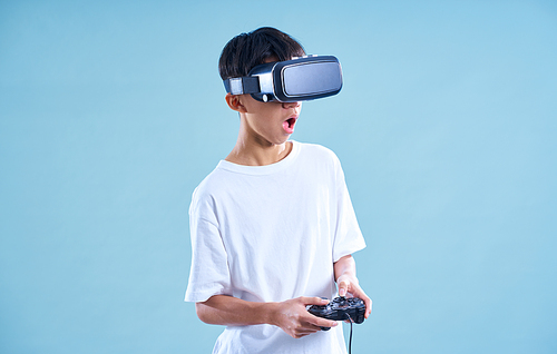 Young teenage boy playing excited with a VR virtual reality headset with game controller .