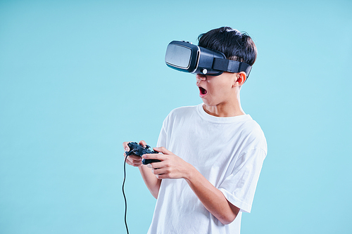 Young teenage boy playing excited with a VR virtual reality headset with game controller .
