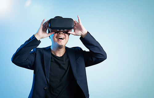 Asian businessman be excited during the view of VR experience with blue background