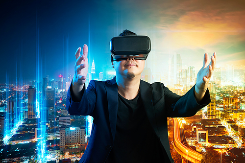 The young man wearing virtual reality goggles with amazing futuristic blue and orange color mix media cityscapes virtual imaging background .