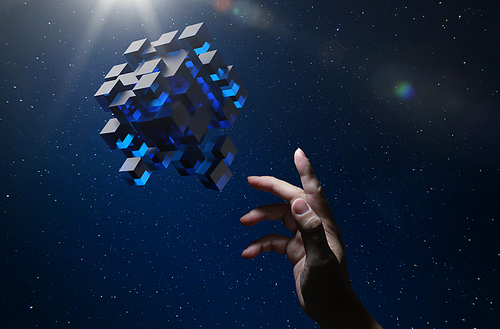 Unknown hand touching floating blue shiny cube on dark background .