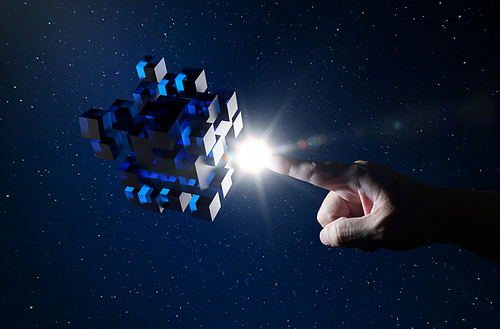 Unknown hand touching floating blue shiny cube on dark background .