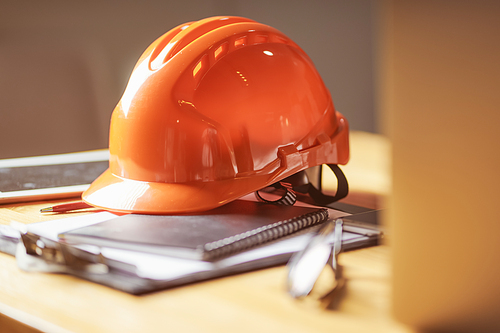 Laptop ,glasses, note book ,phone ,blueprint and orange safety helmet stacking on table at construction site for Engineer, foreman and worker , selective focusing .