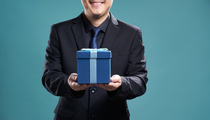 Close up of man with blue present box , isolated on light blue background .