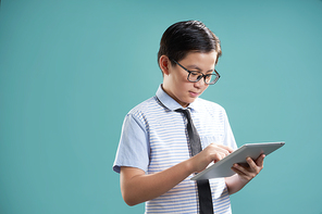 Smart asian boy using digital tablet to learning , isolated on mint green background .