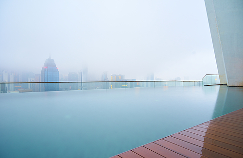 Swimming pool on roof top with beautiful city skyline view,early morning with mist ,  kuala lumpur malaysia.