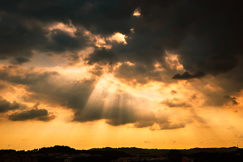 Dramatic sunlight or sun ray through the clouds at sunset sky background .