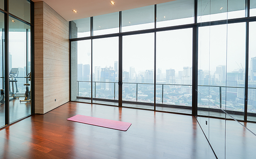 Unrolled yoga mat on wooden floor in fitness center with cityscape  scene