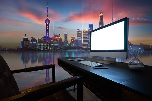 Computer on desktop with Shanghai city skyline view in dusk.