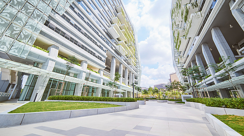 Low angle perspective view of empty pavement and modern office building with green eco concept balcony .