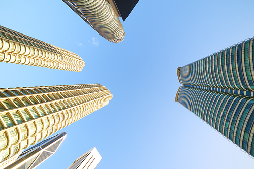 Low angle shot of modern glass city buildings with clear sky background.