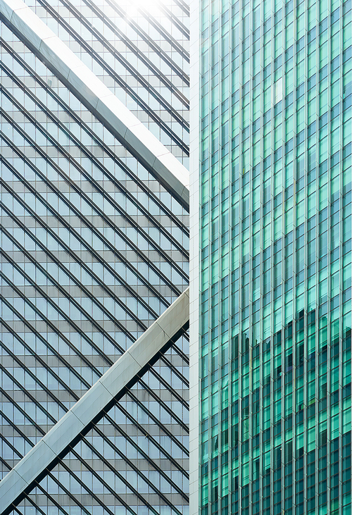 Closeup view of generic modern office skyscrapers ,high rise buildings with abstract geometry glass facades on a bright sunny day . Concepts of finances and economics background.