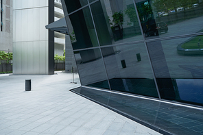 Empty ground in front of modern steel and glass wall buildings .