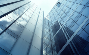 Low angle view of generic modern office skyscrapers ,high rise buildings with abstract geometry glass facades on a bright sunny day . Concepts of finances and economics background.