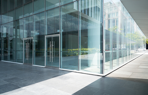 Empty ground in front of modern glass wall facade buildings .