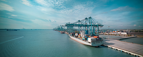Logistics container cargo ship with working crane bridge in import export terminal port, international logistics transport industry background, Panorama arial view.