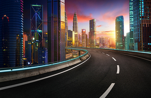 Highway overpass with modern city skyline and  skyscrapers at sunset.