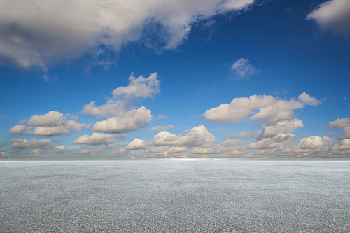 Empty asphalt floor with white clouds and blue sky .