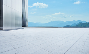 Perspective view of empty concrete tiles floor with modern architecture and beautiful landscape, Morning scene