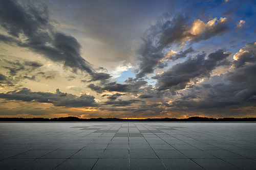 Empty tiles ground floor with dramatic sunset sky .