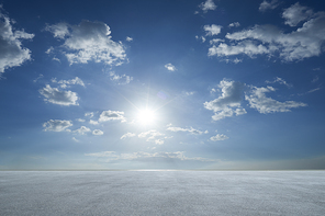 Empty asphalt floor with blue sky and bright sun .