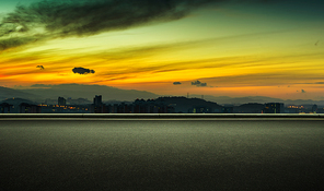 Asphalt empty road side with dramatic orange color sunrise sky background .