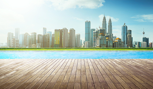 Wooden perspective brown empty floor in front of swimming pool with city skyline background .
