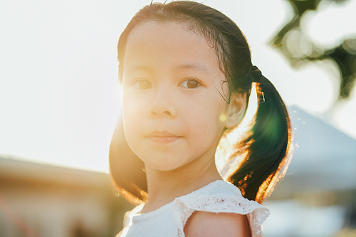 close up portrait of little asian girl with dimples in park during