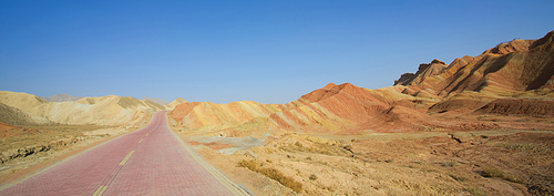 Long empty red brick road in desert with  clear blue sky .