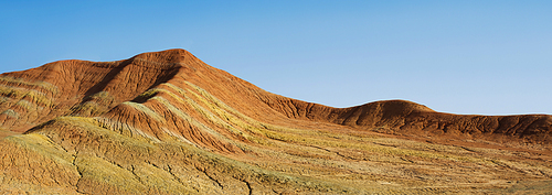Striped shaped hills in desert with clear blue sky .