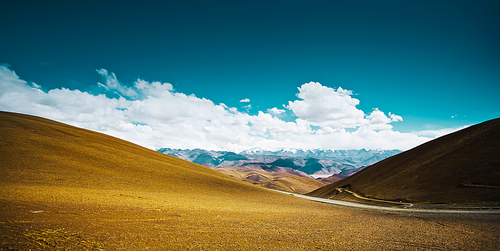 Beautiful scenery in Tibet with yellow hill  against blue and white clouds sky .