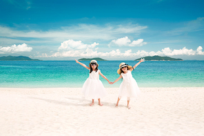 Two asian young sister holding hands on the beach ,enjoying tropical sea vacation .