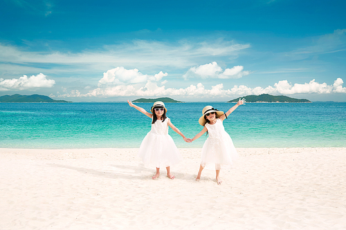 Two asian young sister holding hands on the beach ,enjoying tropical sea vacation .