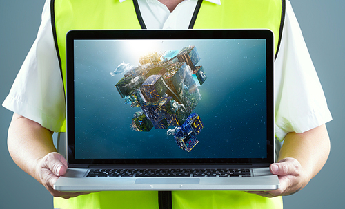 Engineer in safety suit and using laptop showing fantasy puzzle cube of city and landscapes floating in the air.