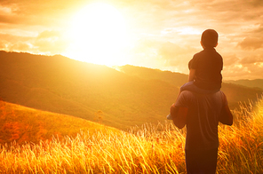 The boy sits on the shoulders of his father. Broga hill background .Golden hour scene .
