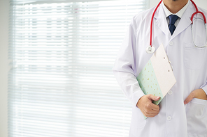 Doctor with a stethoscope and taking notes with bright background .