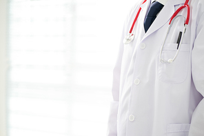 Unknown doctor posing in the office, he is wearing a stethoscope .