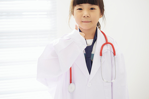 Portrait of little girl dressed as a doctor with a stethoscope and hands with thumbs up .