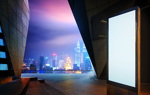 Blank advertising billboard at night against modern building city skyline background .