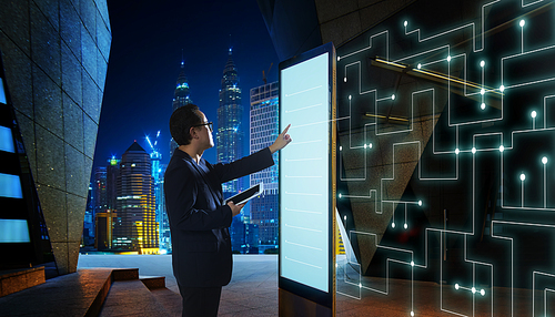 Smart businessman touch the screen to search the information of intelligent communication network of things . Night scene with modern city background .