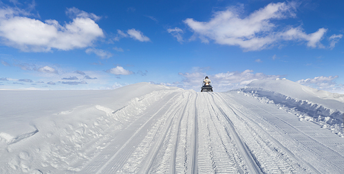 Snowmobile driving on a snow hill with beautiful sunny day
