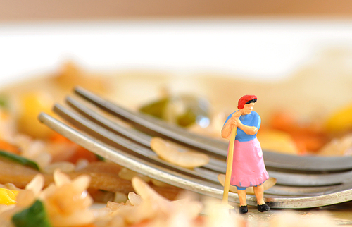 Miniature maid gets ready to wash dishes without. Macro photo