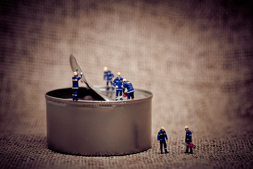 Group of miniature workers opening a can. Color tone tuned macro photo. Macro photo