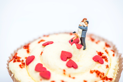 Miniature loving couple on top of cupcake. Macro photo